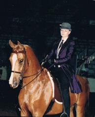 Archival image of Lisa Levasseur competing in an equestrian event, dressed in traditional show attire and focused on guiding her horse.